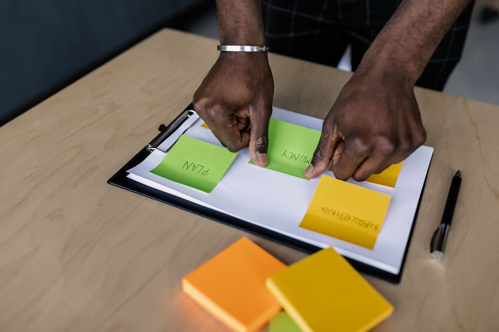 Handen die een planning met gekleurde notities ordenen